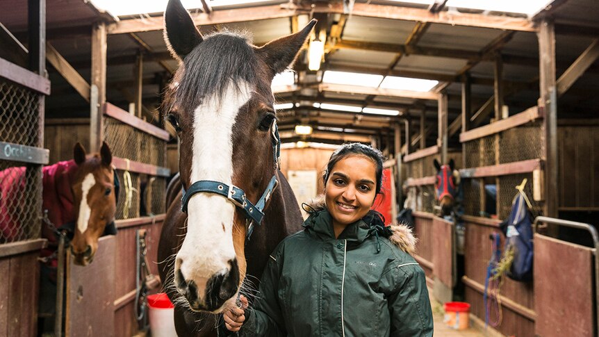 Zoya Patel with her horse Penny in a stable.