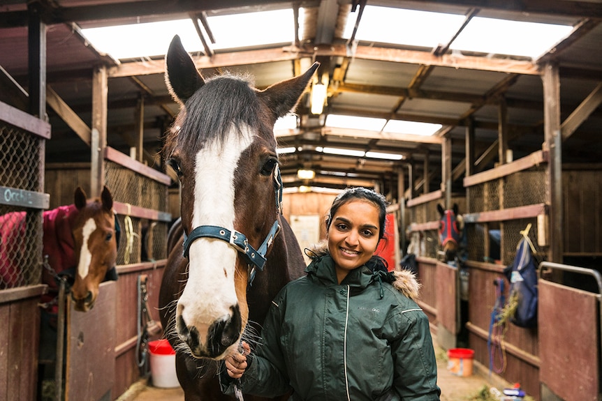 Zoya Patel with her horse Penny in a stable.