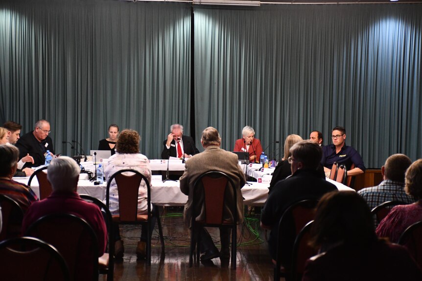 Members of a parliamentary committee sitting at desks, listening to evidence from residents at Cobar