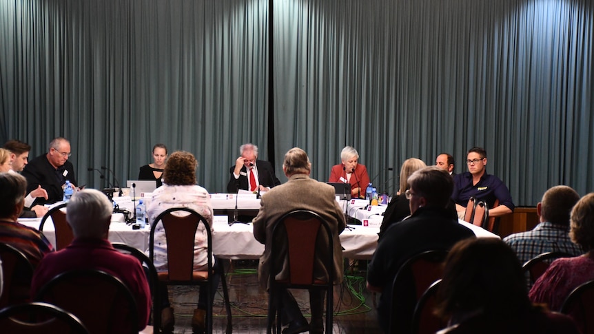 Members of a parliamentary committee sitting at desks, listening to evidence from residents at Cobar