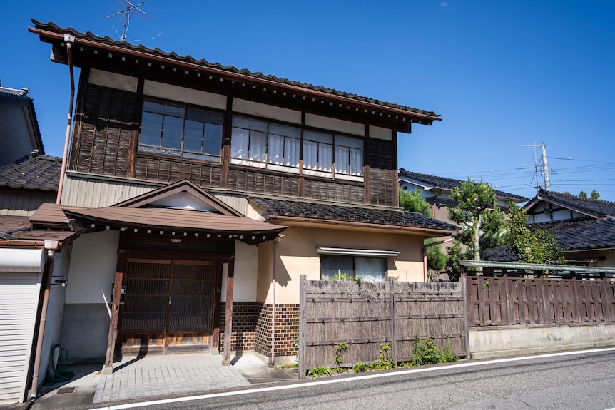 A view of a run down home with rocks out front.