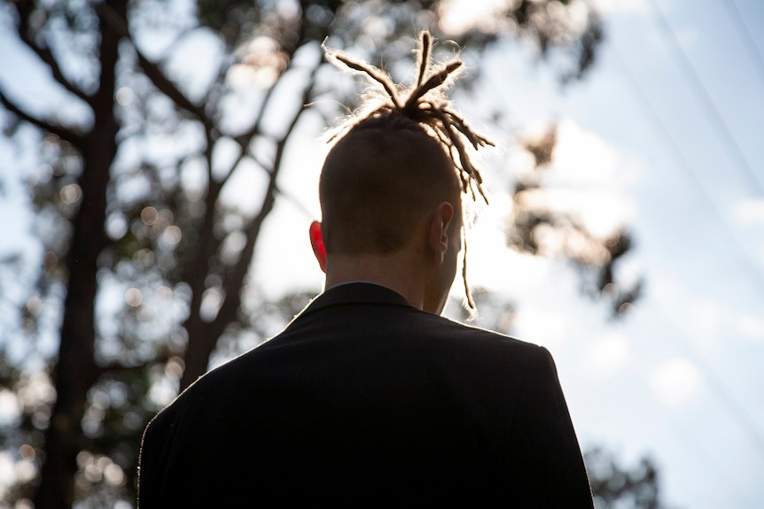 The back of a young man's head framed by the sun
