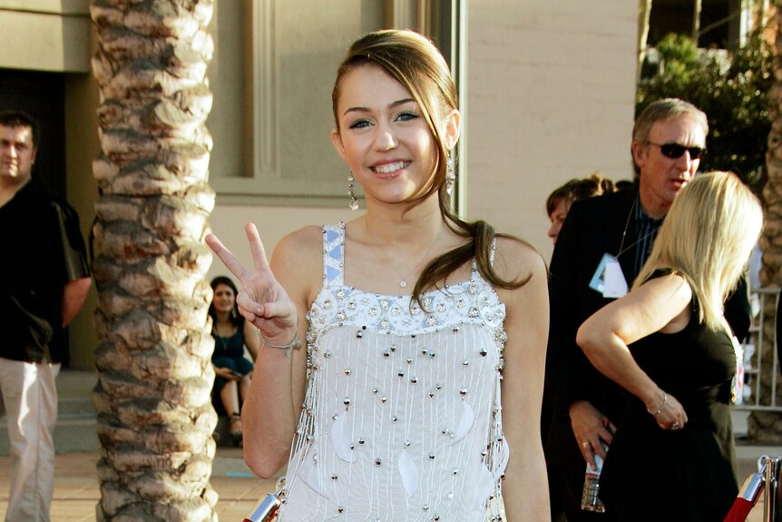 A teenage Miley Cyrus walks the red carpet at the 2006 American Music Awards.
