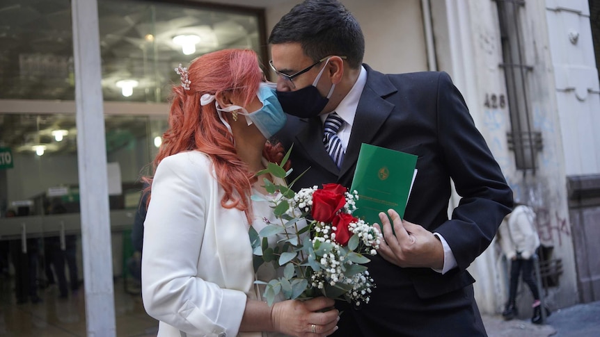 Newlyweds kiss while wearing face masks