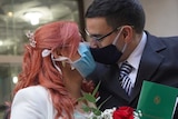 Newlyweds kiss while wearing face masks