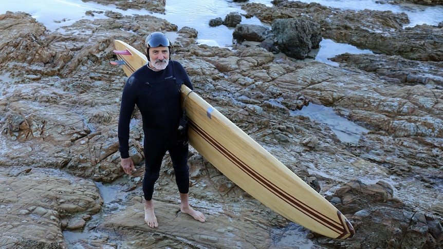 Former Greens MP Ian Cohen with his surfboard at The Pass in Byron Bay.