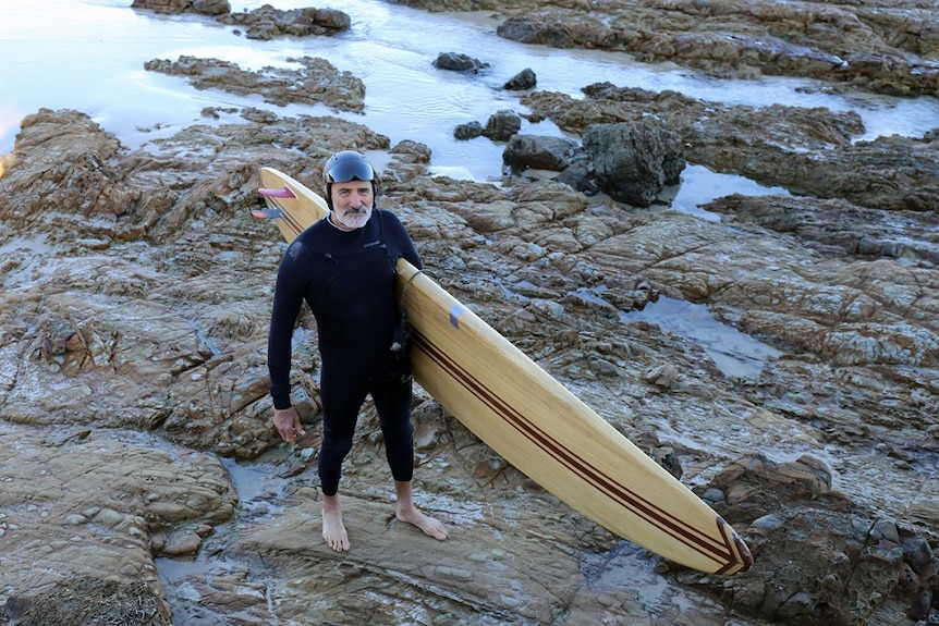 Former Greens MP Ian Cohen with his surfboard at The Pass in Byron Bay.