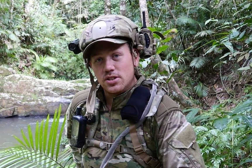 A man wearing camouflage in the bush.
