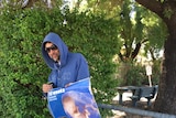 A protester wearing a blue hooded jumped and holding a poster