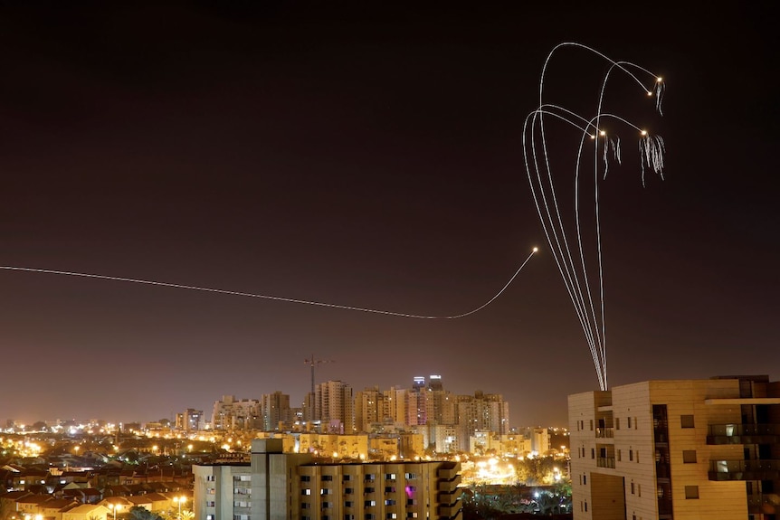 Rockets leaving a trail of light over a city.