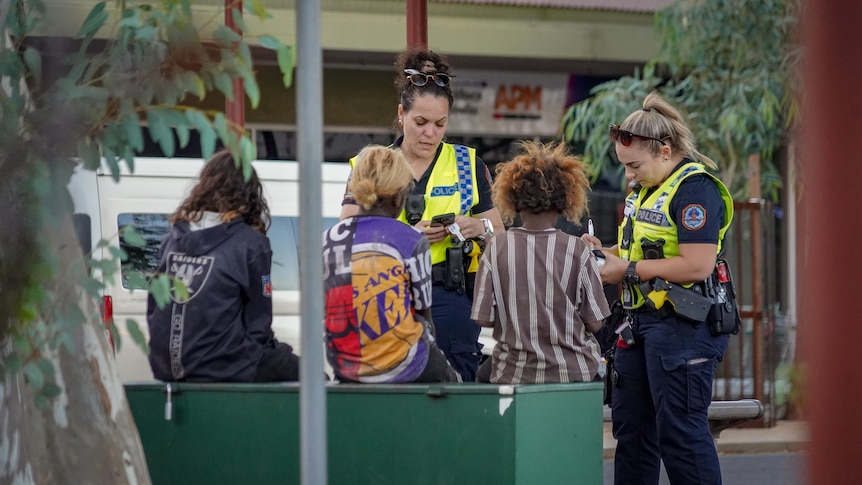 Two police officers talk to three kids in the Alice Springs CBD.