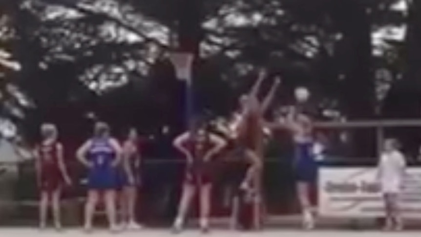A blurry image showing a netballer standing on another netballer's back during a game