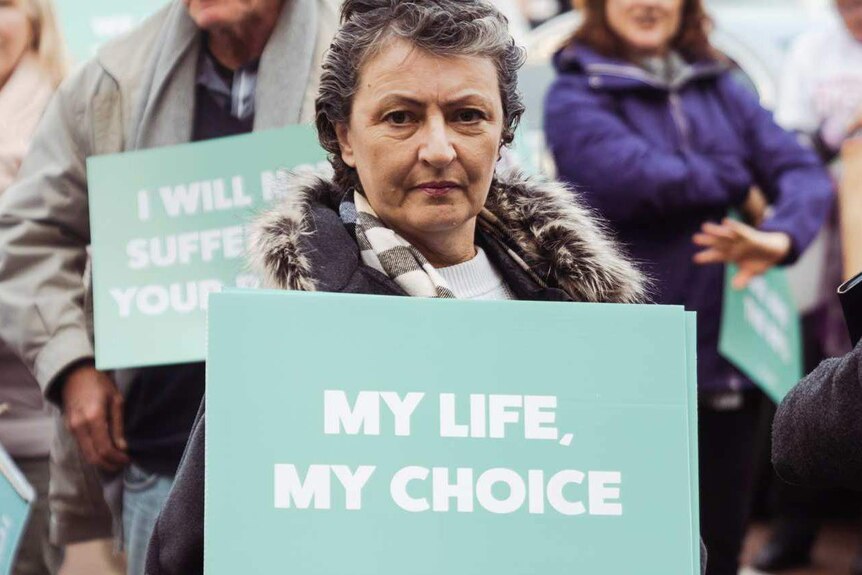 Voluntary euthanasia supporter holds a "My Life, My Choice" sign.