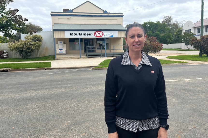 cassie jackson stands in front of a deserted IGA store front