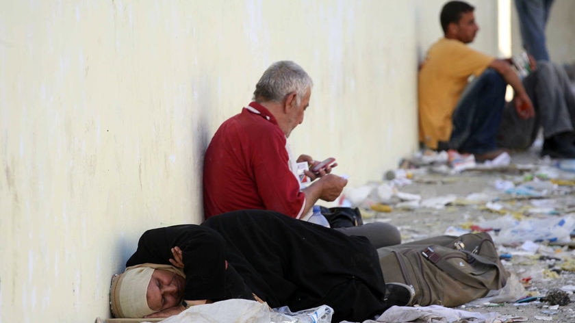 Palestinians sit amid debris waiting to cross to the West bank at the Erez Crossing.