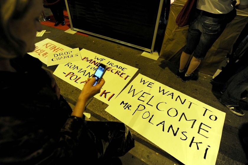 A woman takes a photo of signs supporting Oscar-winning director Roman Polanski