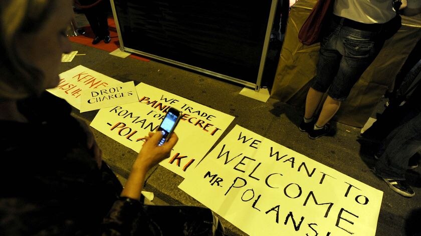 A woman takes a photo of signs supporting Oscar-winning director Roman Polanski