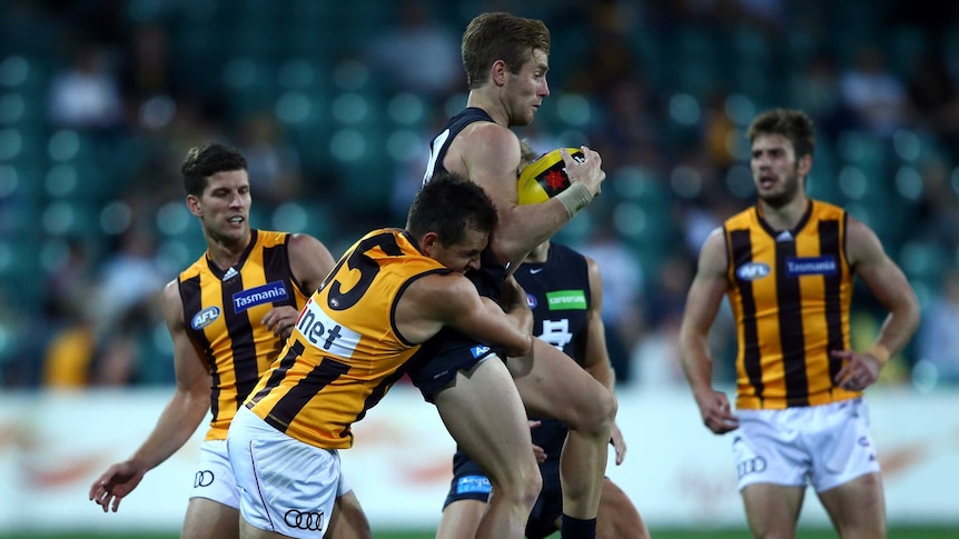 Carlton's Nick Graham is tackled by Hawthorn captain Luke Hodge