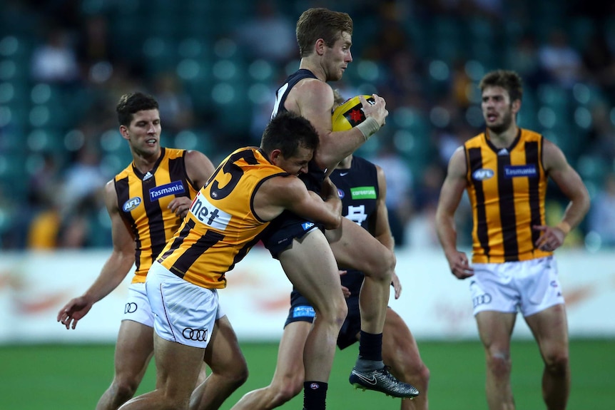 Carlton's Nick Graham is tackled by Hawthorn captain Luke Hodge