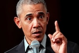 Barack Obama points his left index finger while speaking into a microphone.