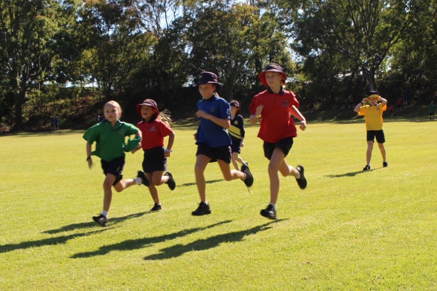 A handful of kids running across school oval.