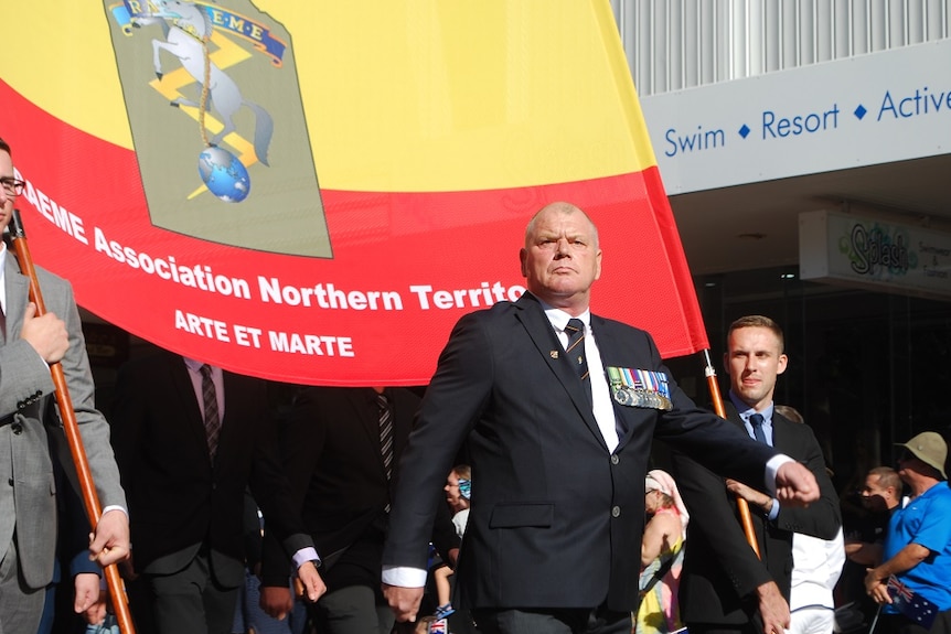 Men wearing medals march in Darwin