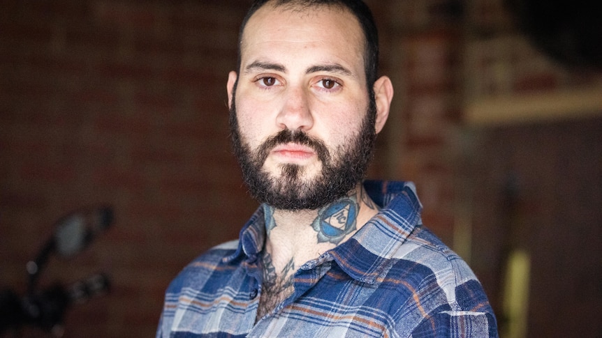 A bearded man with tattoos on his neck.