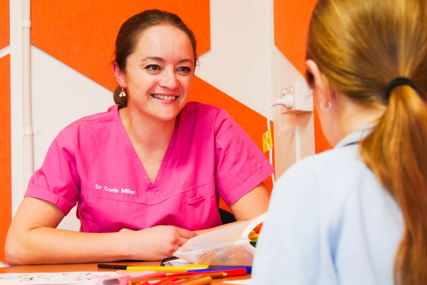 a woman smiling at a child at a table