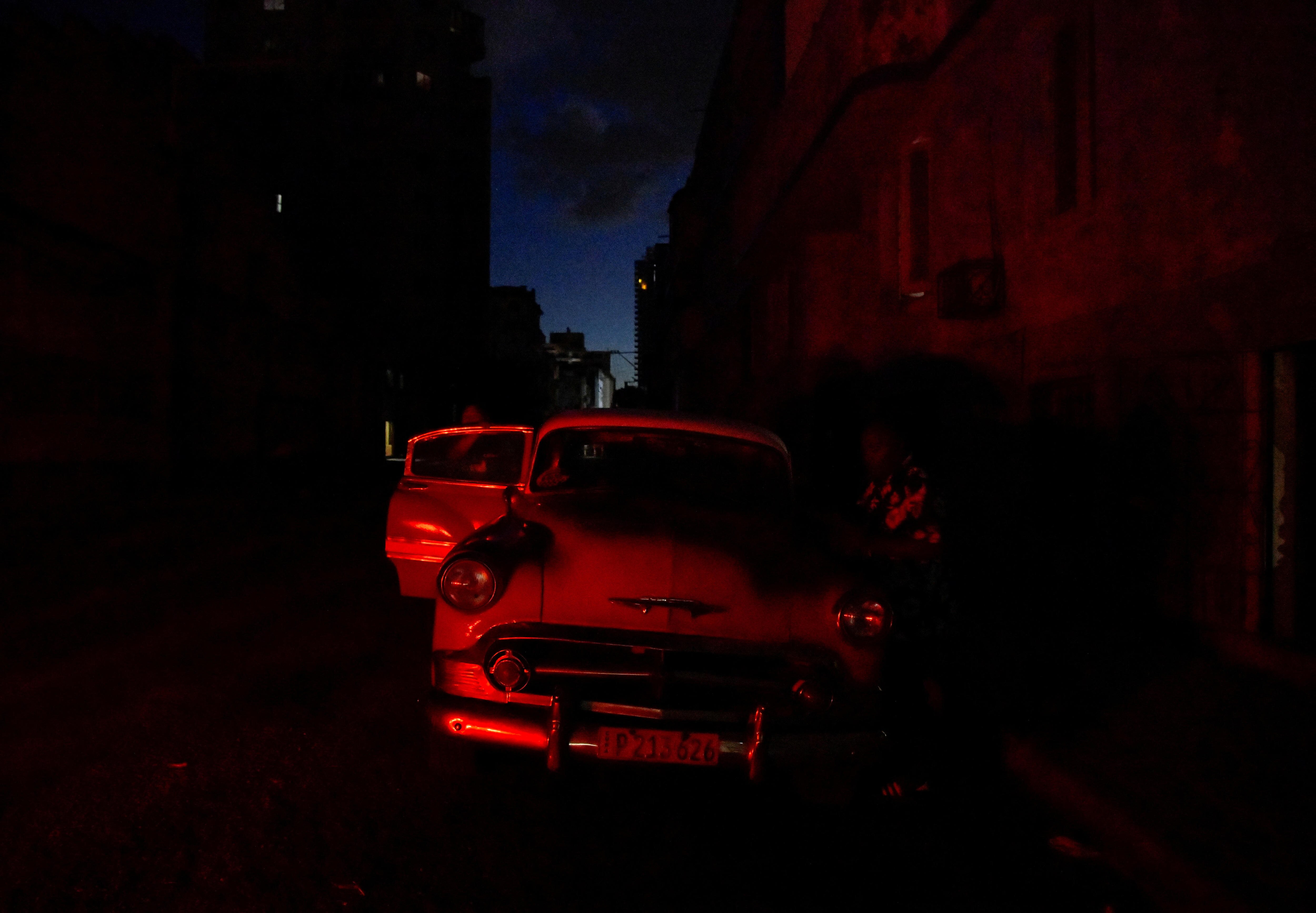 A person cleaning a car under a red light. 