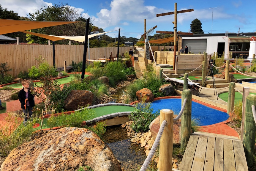 mini golf facility with boy hitting a golf ball