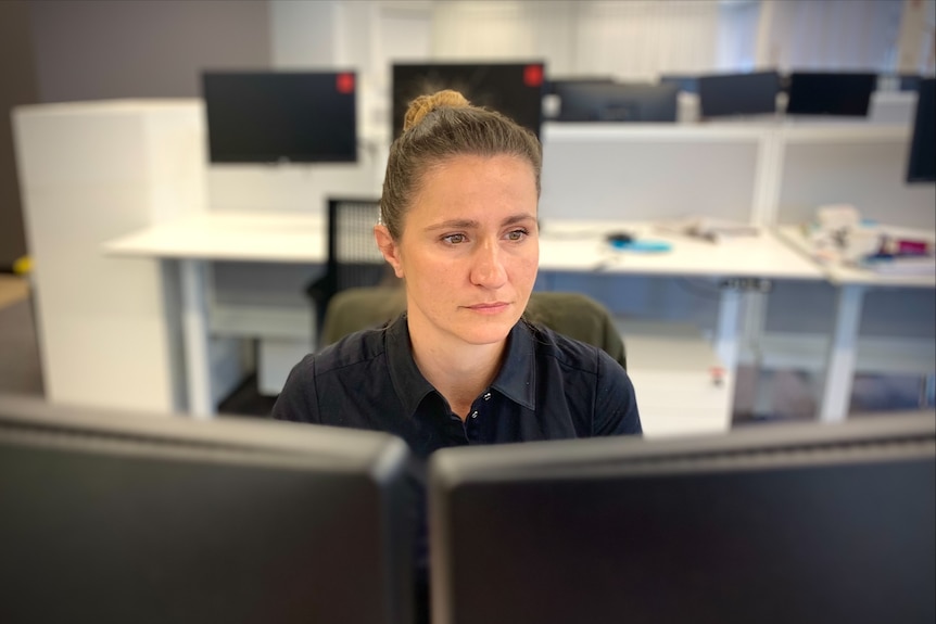 Jana Jevcakova seated behind two computer screens.