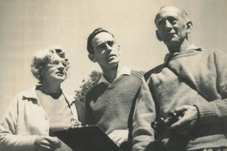 A black and white photo of a woman and two men.