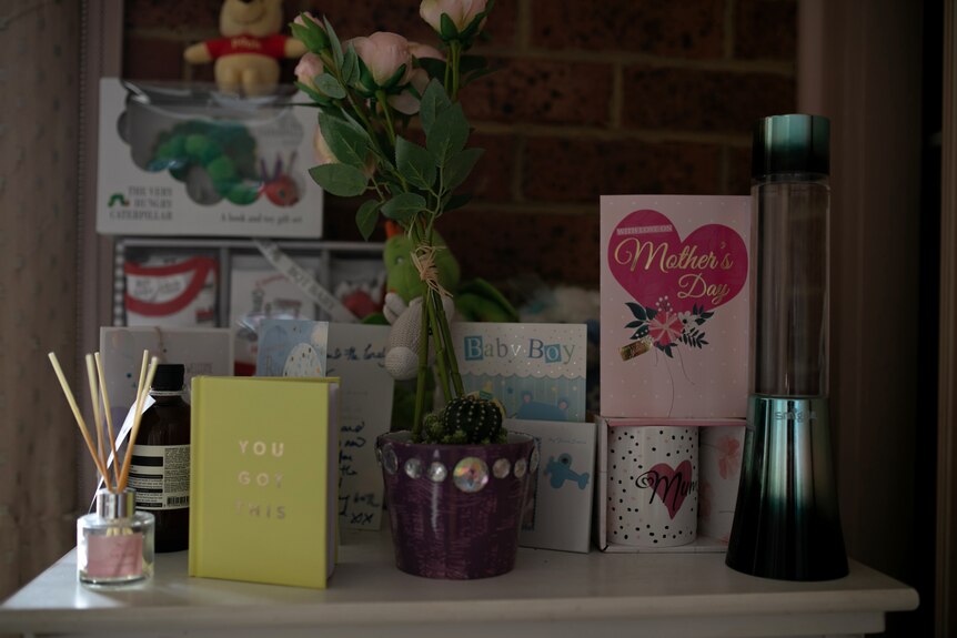 Cards, flowers and gifts sit on a table. The cards say 'Baby boy' and 'Mother's Day'. 