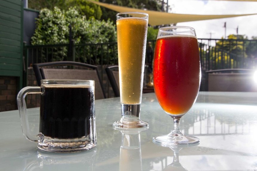 Three beers sit on a table.