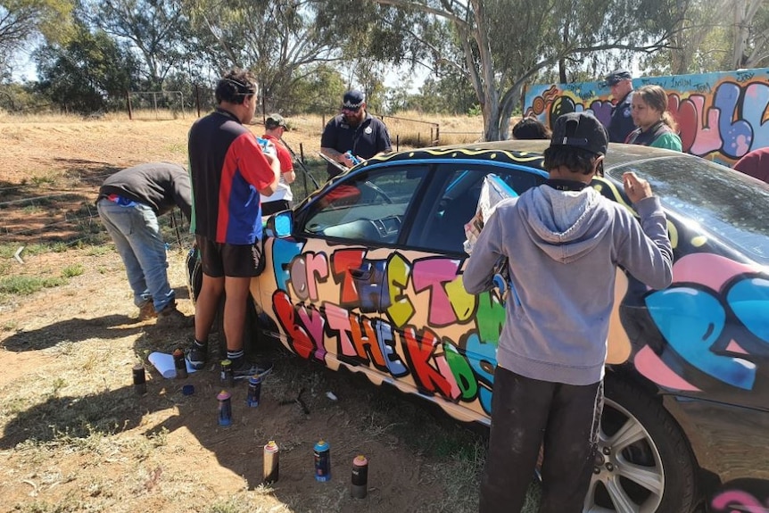 Teenagers spray paint sedan car with assistance of police officers