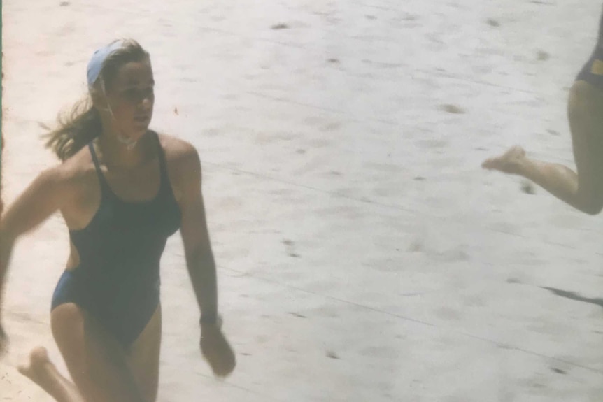 Teenage girl in swimming costume sprinting on beach in competition