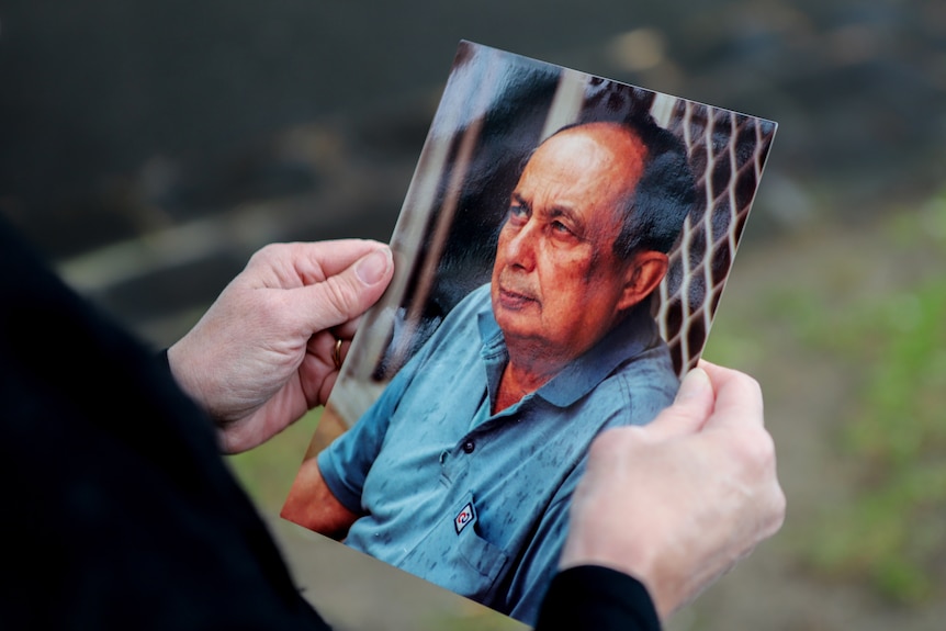 Hands holding a photo portrait of an old man.