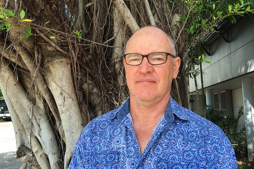 Skinnyfish Music Managing Director Mark Grose stands in front of a mangrove tree.