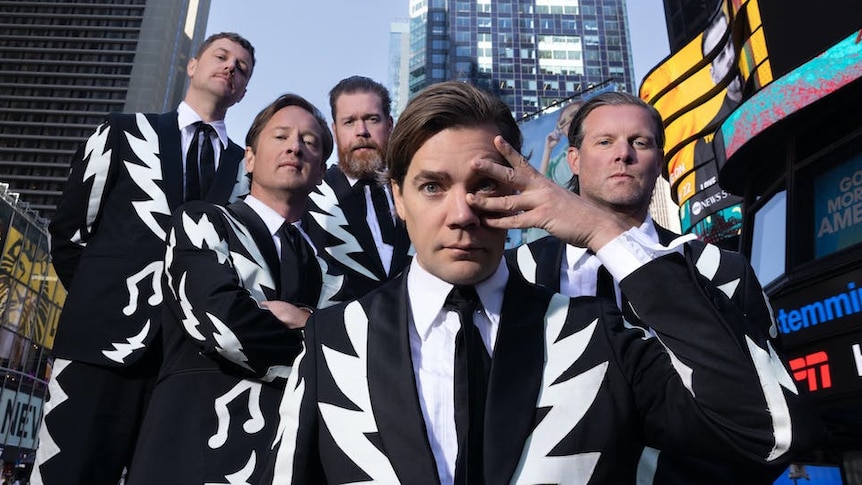 The Hives pose in Times Square wearing matching black-and-white suits with lightning bolt lapels