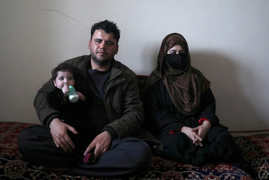 Hamid and his wife Fatima pose with baby Sohail in their house in Kabul on January 7, 2022.