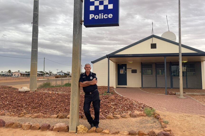 Senior Constable Stephan Pursell leans on a police sign in Channel Country
