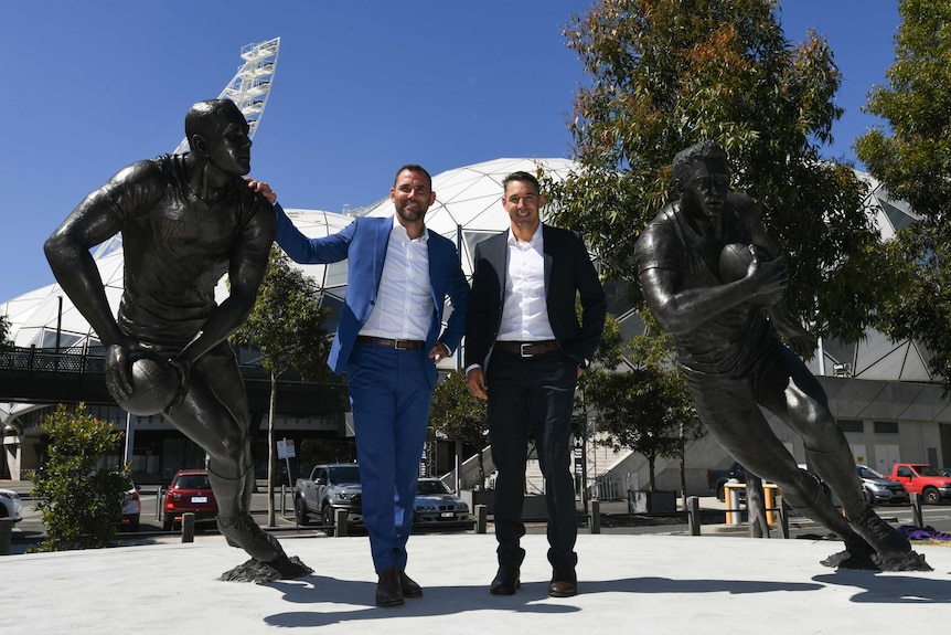 Cameron Smith and Billy Slater stand next to their respective statues in Melbourne.