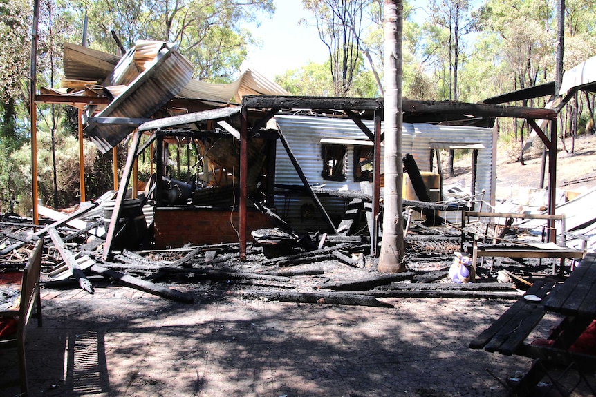 The remnants of a home destroyed by fire in a bush setting.