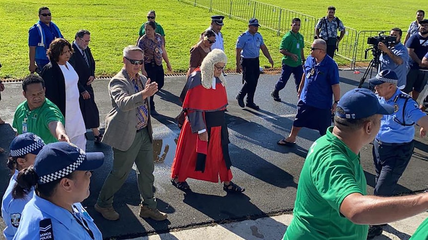 Samoa's Chief Justice Satiu Simativa Perese arrives at parliament in Apia, flanked by police and officials.
