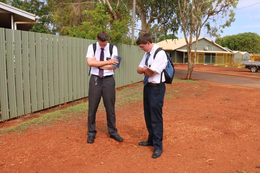 Missionaries pray before door knocking
