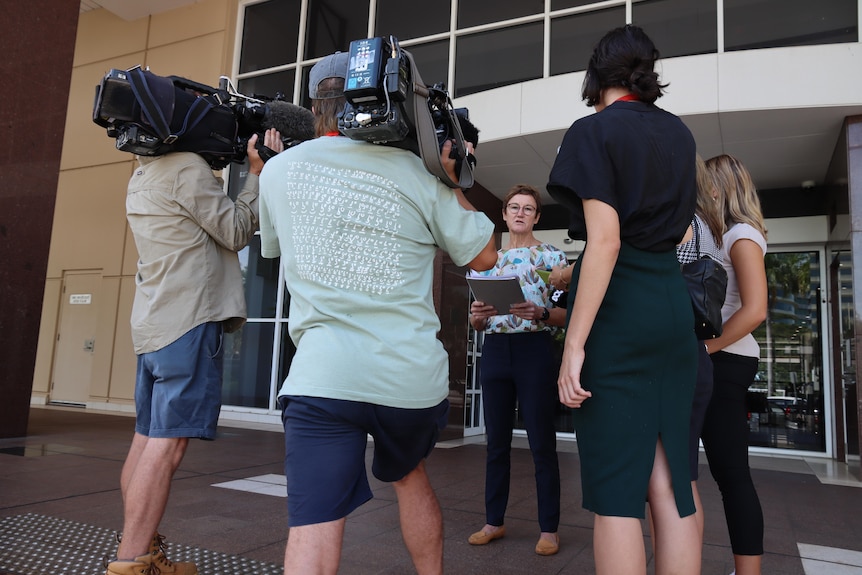 A woman stands speaking to media outside court.