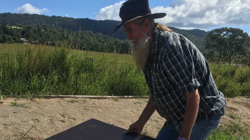 David Bauer with long beard and wizard hat lifts a large piece of steel sheet.
