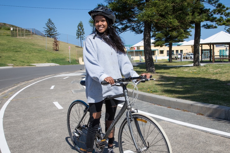 A young woman on a bike smiles at the camera
