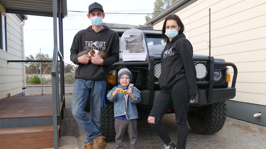 Nikita Shaw, Jack Dowling and their three-year-old son Ahren standing in front of a 4WD vehicle at a Broken Hill caravan park.