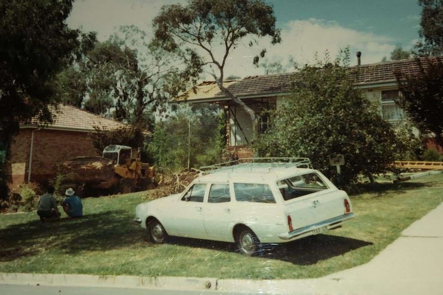 An old home with work trucks outside, ready for renovation.